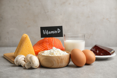 Photo of Paper with phrase VITAMIN D and fresh products on light table