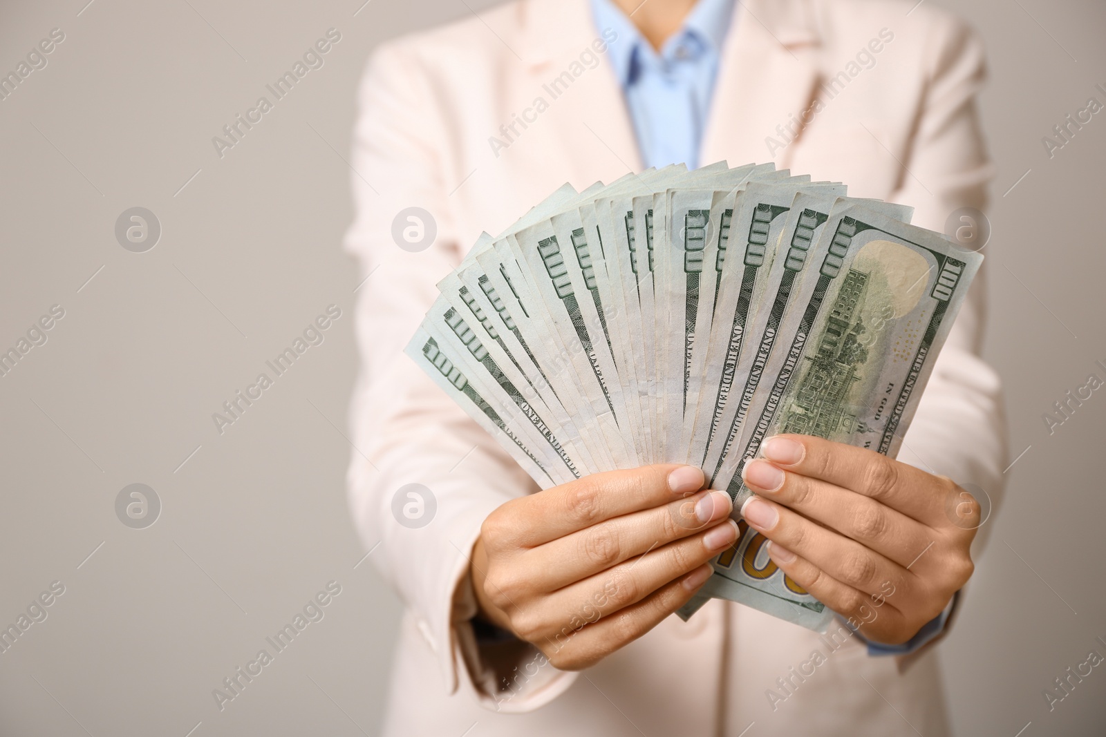 Photo of Young woman holding dollar bills on light grey background, closeup