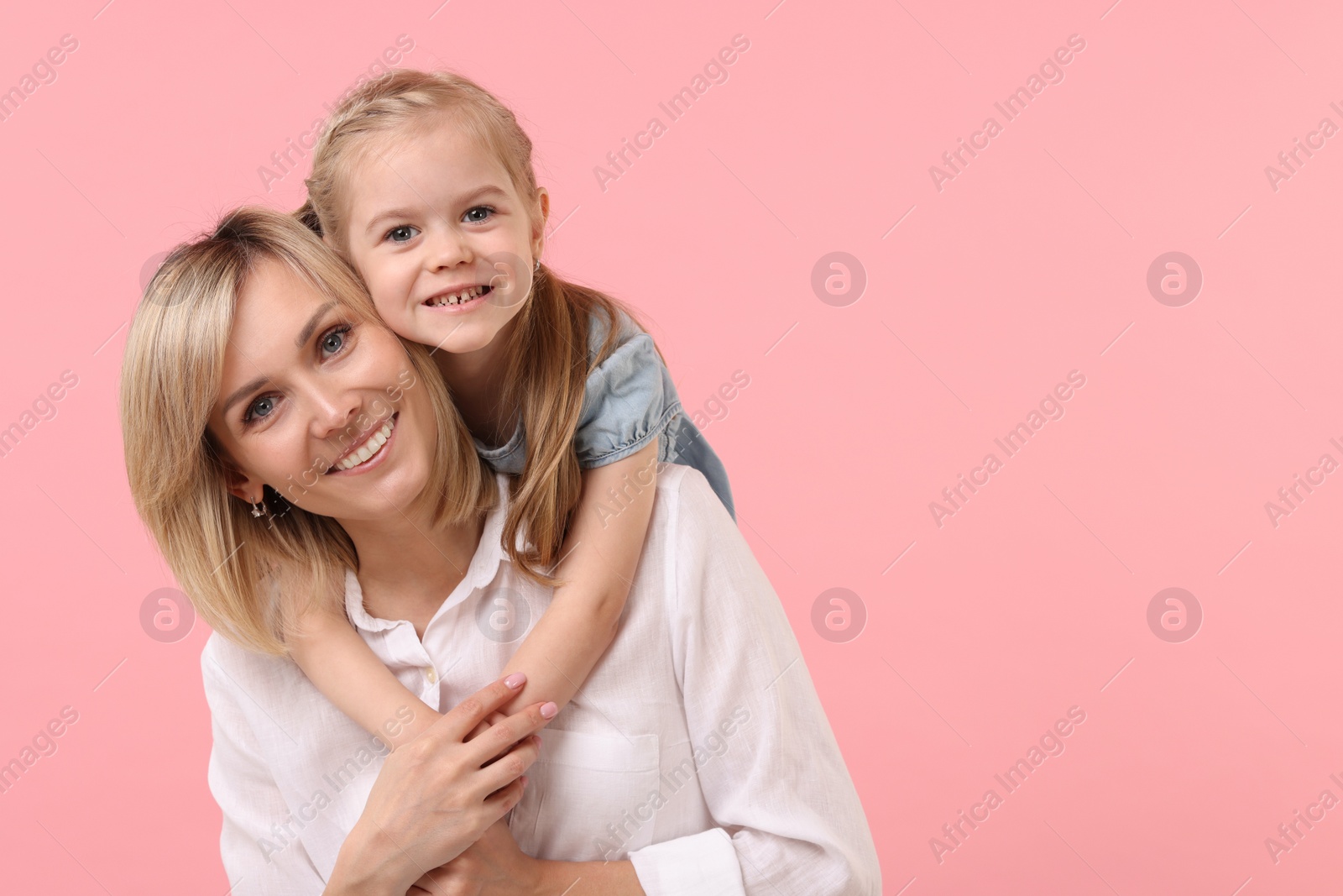 Photo of Daughter hugging her happy mother on pink background. Space for text