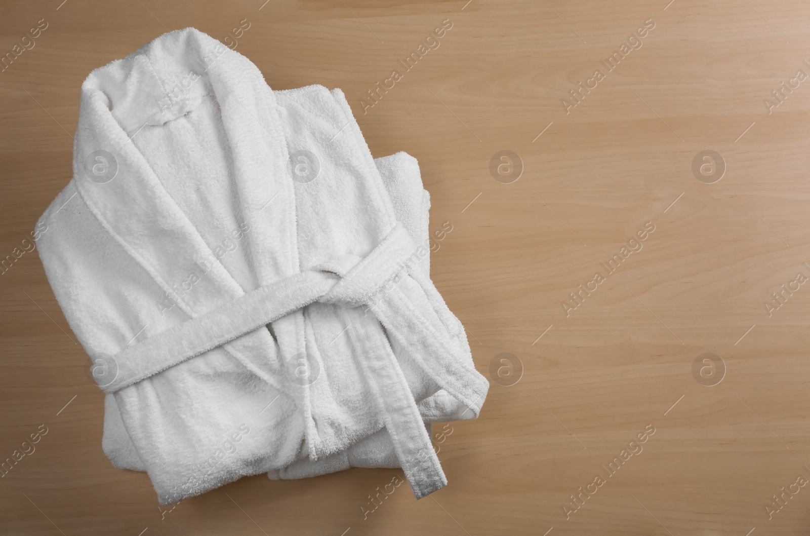 Photo of Clean folded bathrobes on wooden background, top view. Space for text