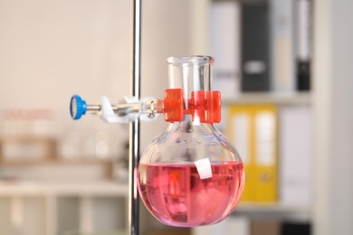 Photo of Laboratory analysis. Glass flask with pink liquid on stand indoors, closeup