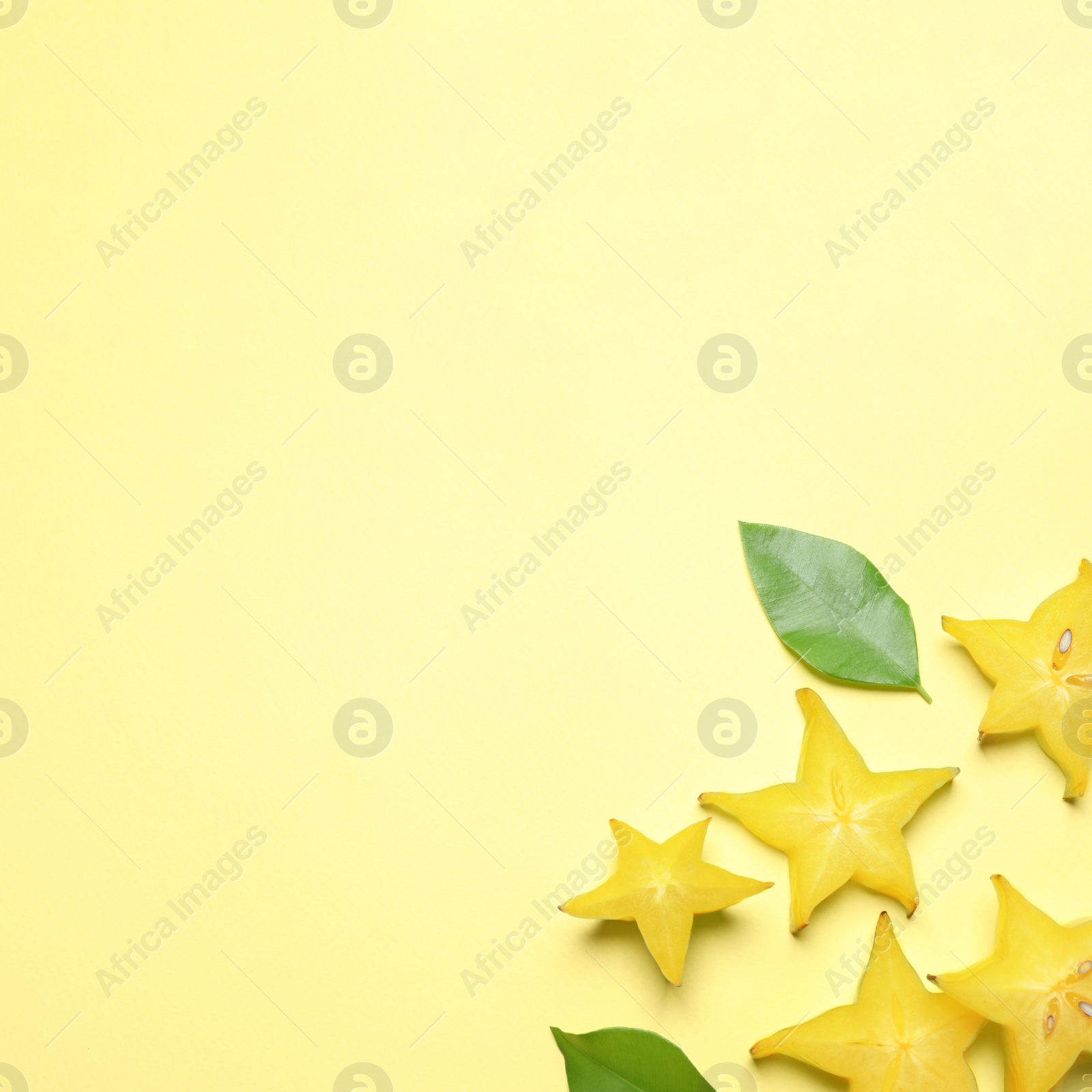 Photo of Delicious carambola slices on yellow background, flat lay. Space for text