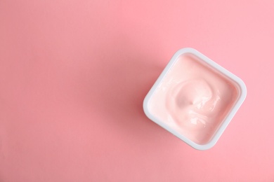 Plastic cup with tasty yogurt on color background, top view