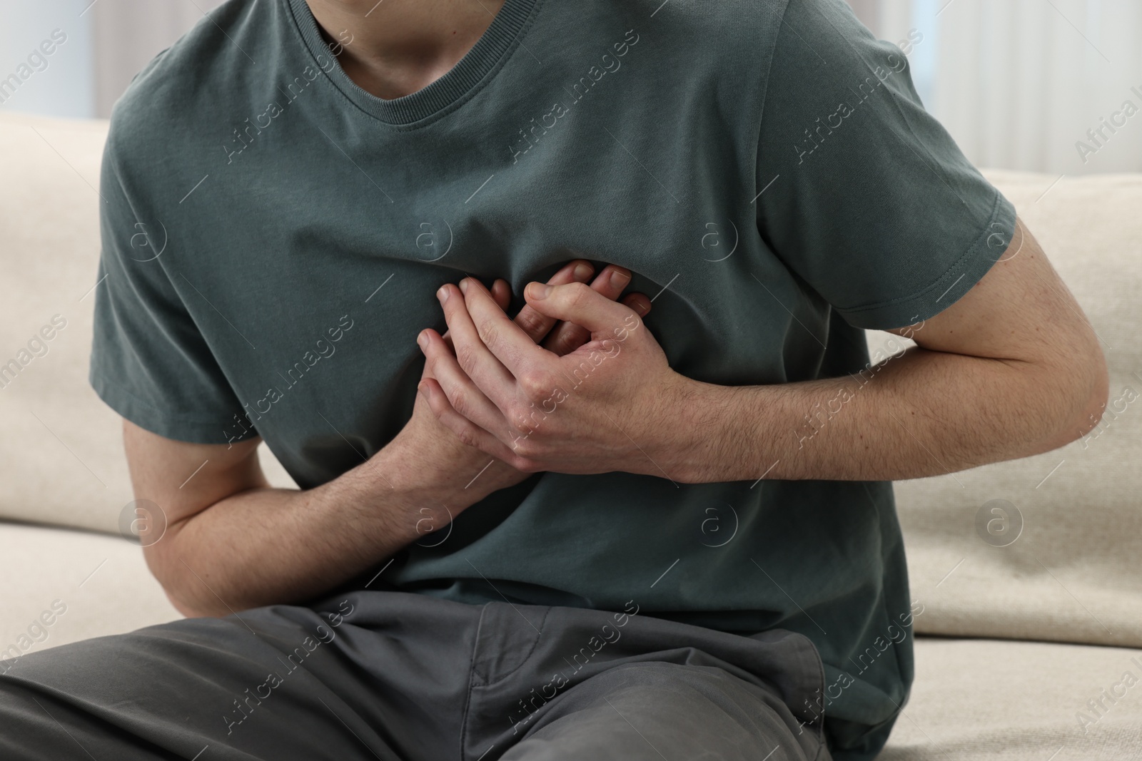 Photo of Man suffering from heart hurt on sofa at home, closeup