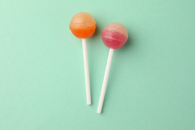 Tasty lollipops on turquoise background, flat lay