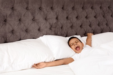 Cute little African-American boy yawning in bed. Sleeping time