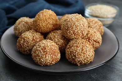 Photo of Many delicious sesame balls on grey table, closeup