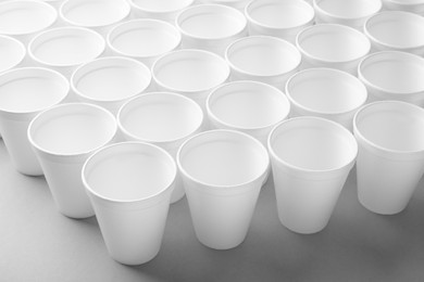 Many styrofoam cups on light grey background, closeup