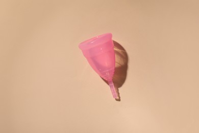 Menstrual cup on beige background, top view