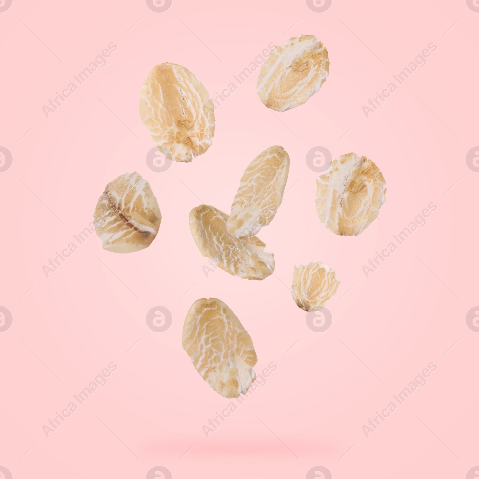 Image of Rolled oat flakes falling on pink background