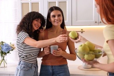 Photo of Happy young friends spending time together in kitchen