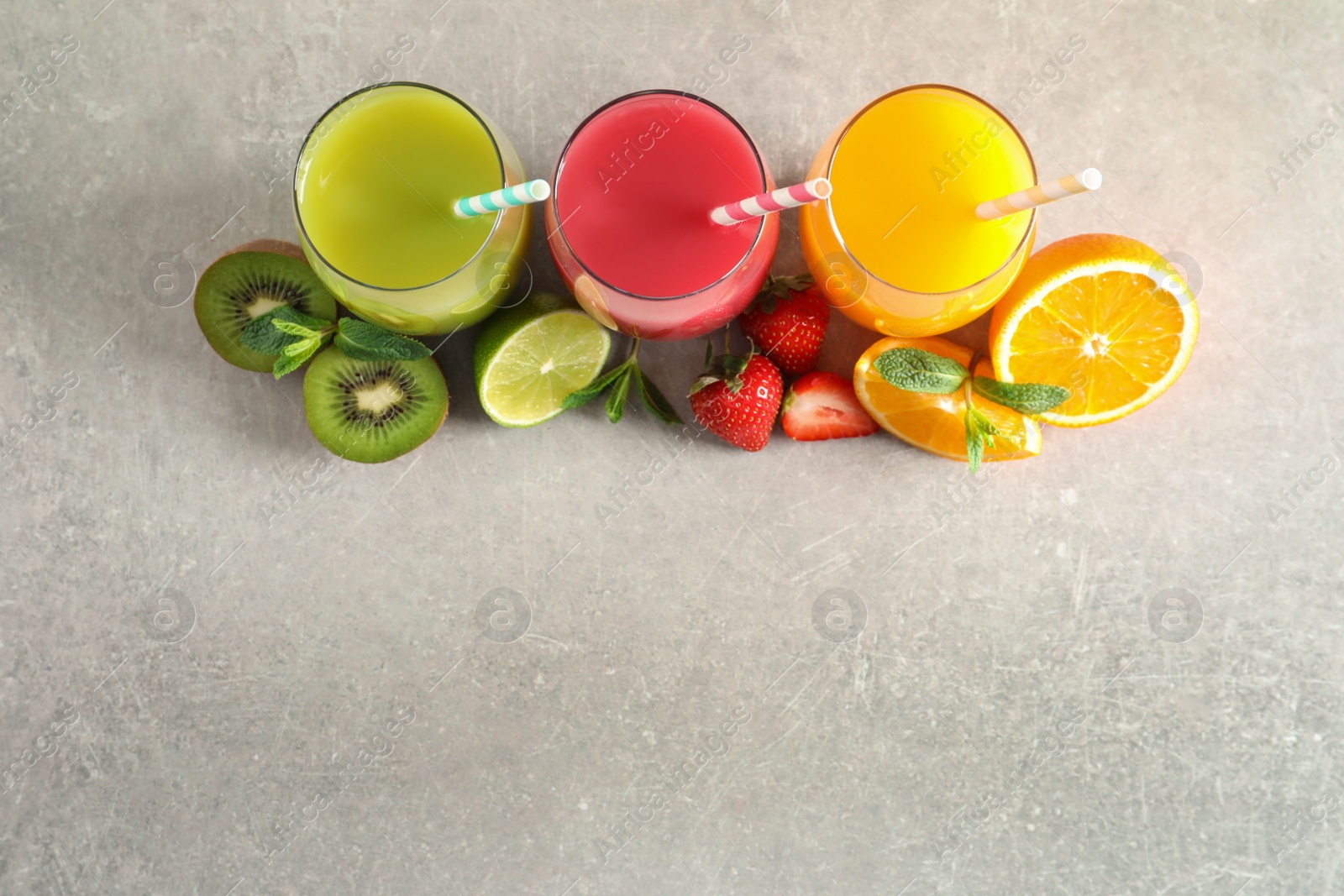 Photo of Flat lay composition with glasses of different juices and fresh fruits on light background. Space for text