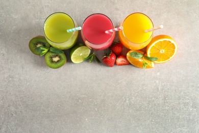 Flat lay composition with glasses of different juices and fresh fruits on light background. Space for text