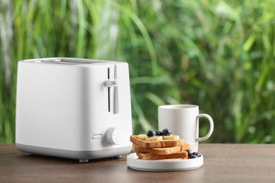 Toaster, roasted bread and coffee on wooden table, space for text