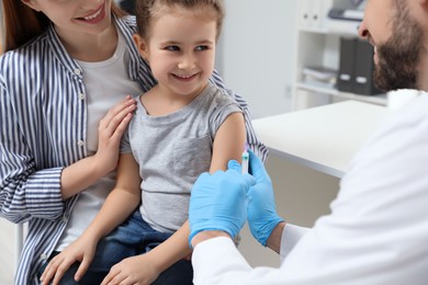 Photo of Children's hepatitis vaccination. Mother with her daughter in clinic. Doctor giving injection to little girl, closeup