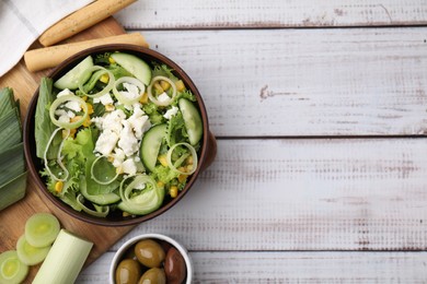 Photo of Bowl of tasty salad with leek and cheese on white wooden table, flat lay. Space for text