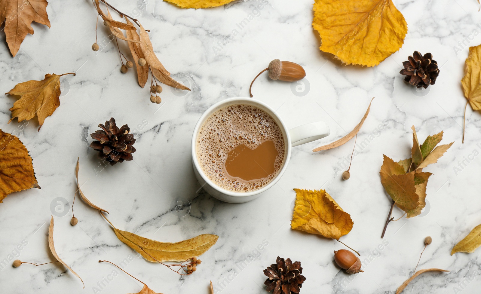 Photo of Flat lay composition with cup of hot drink and autumn leaves on white marble background. Cozy atmosphere