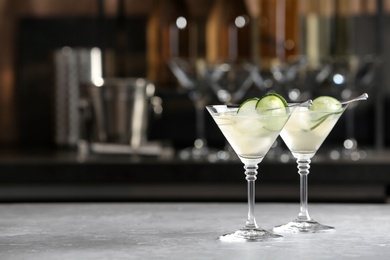 Glasses of tasty cucumber martini on bar counter, space for text