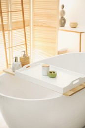 Photo of Scented candles on tray for tub in bathroom. Interior design