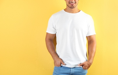 Young man in t-shirt on color background. Mockup for design