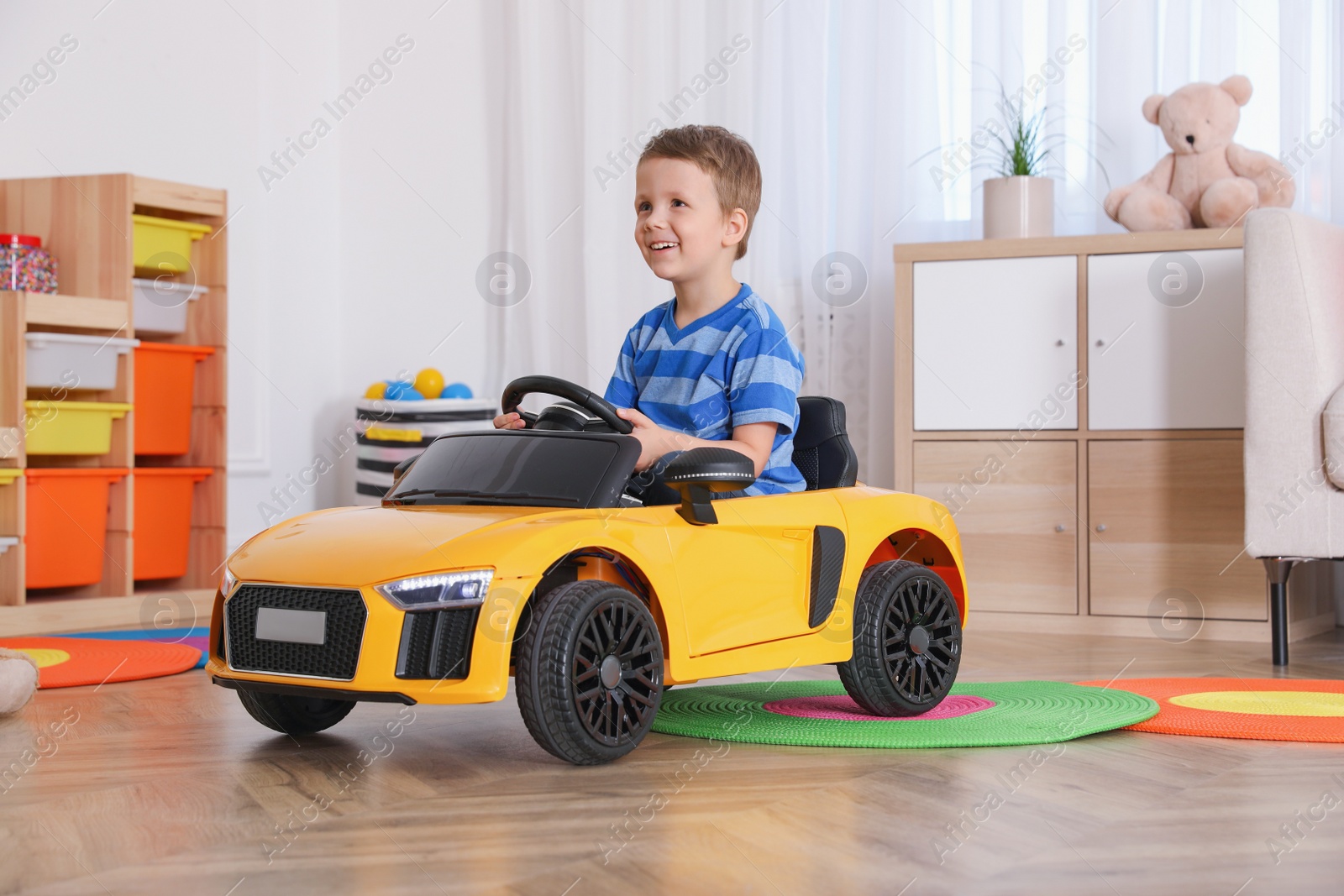 Photo of Little child playing with toy car in room