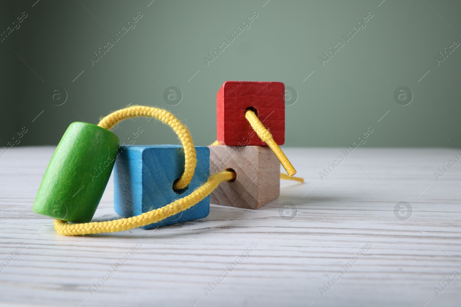 Photo of Wooden lacing toy on light table, closeup and space for text. Motor skills development