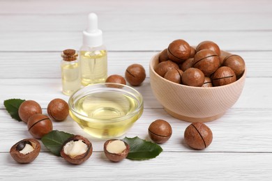Photo of Delicious organic Macadamia nuts and cosmetic oil on white wooden table