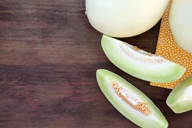 Photo of Tasty whole and cut ripe melons on wooden table, flat lay. Space for text