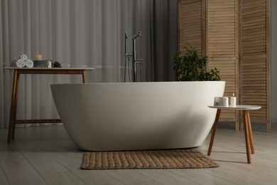 Photo of Ceramic tub, houseplant and spa products in bathroom