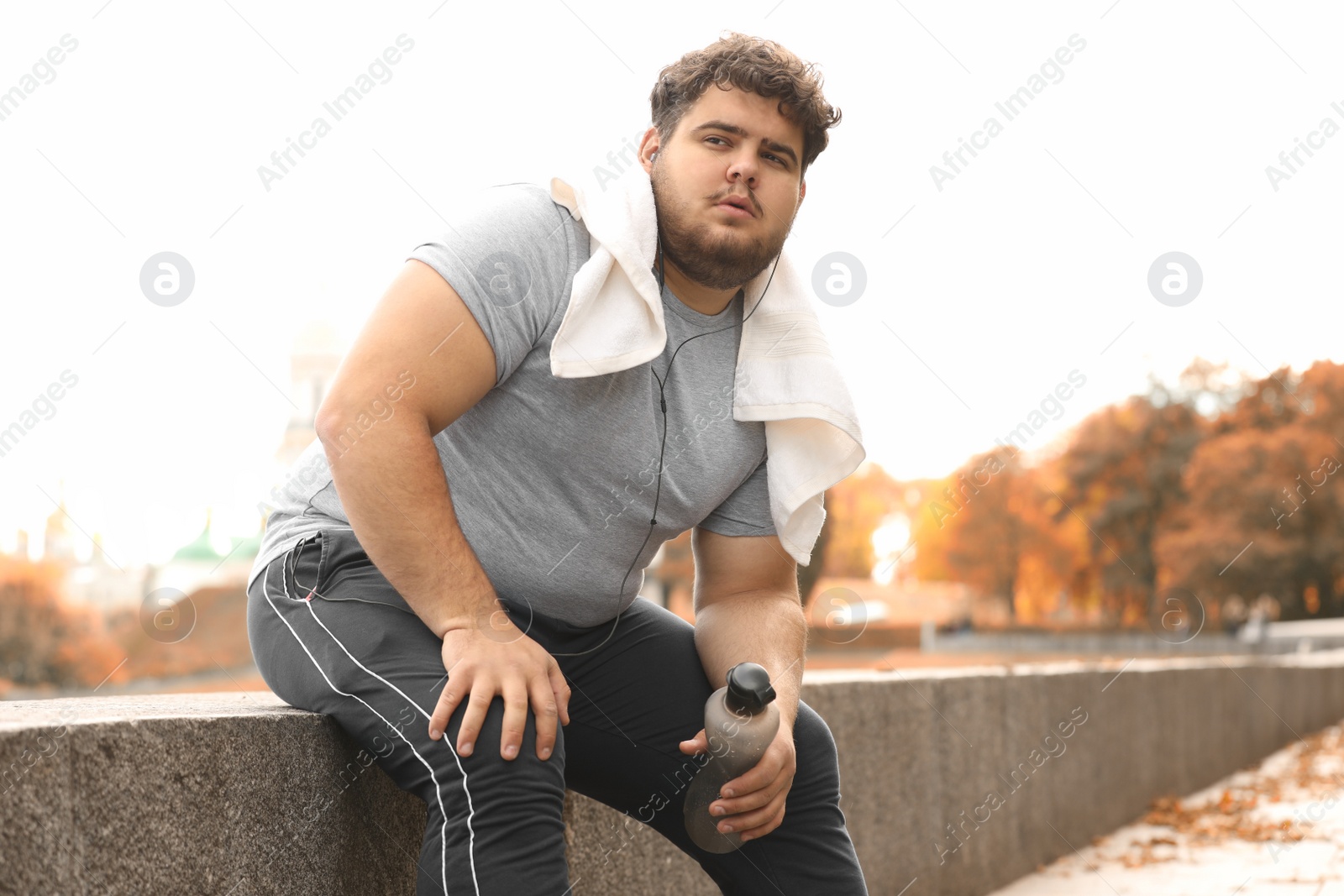 Photo of Young overweight man with towel resting in park