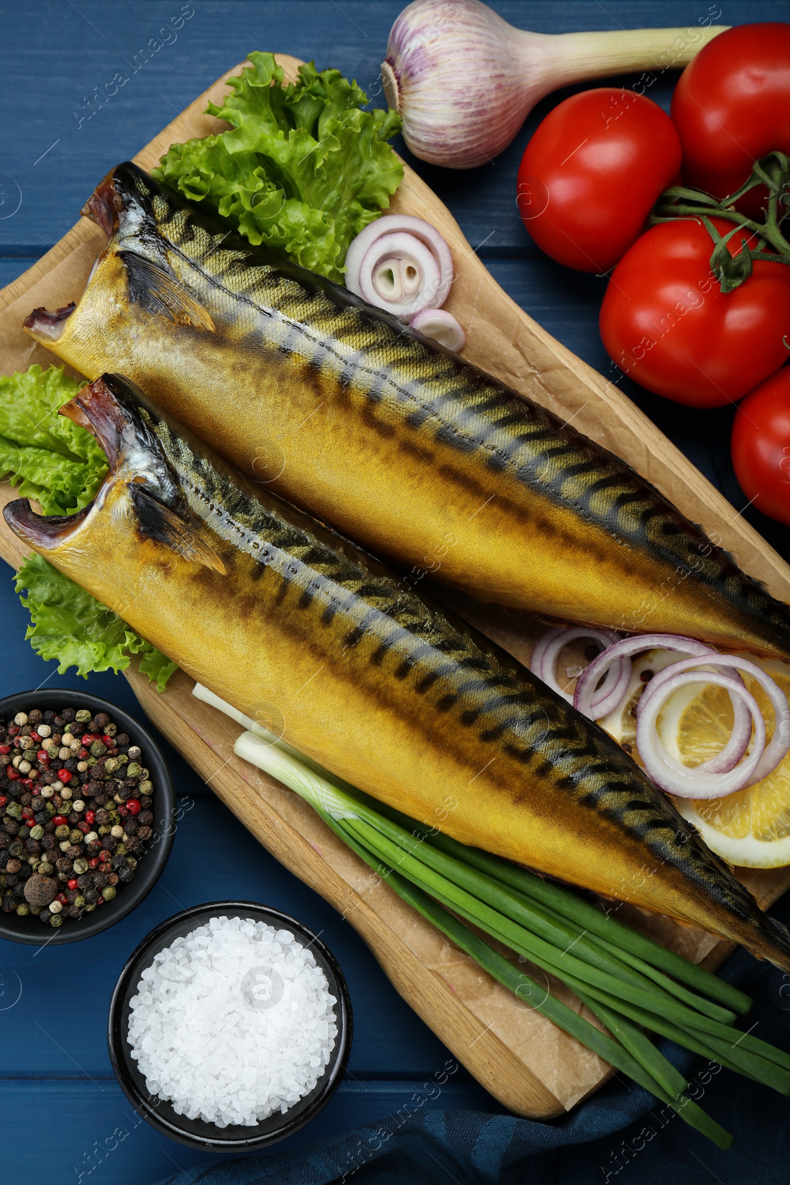Photo of Delicious smoked mackerels and products on blue wooden table, flat lay