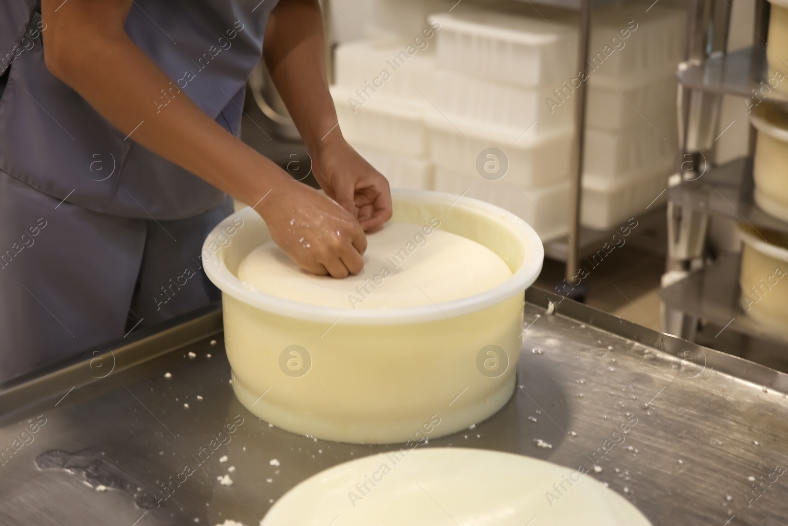 Photo of Worker taking fresh cheese from mould at modern factory, closeup