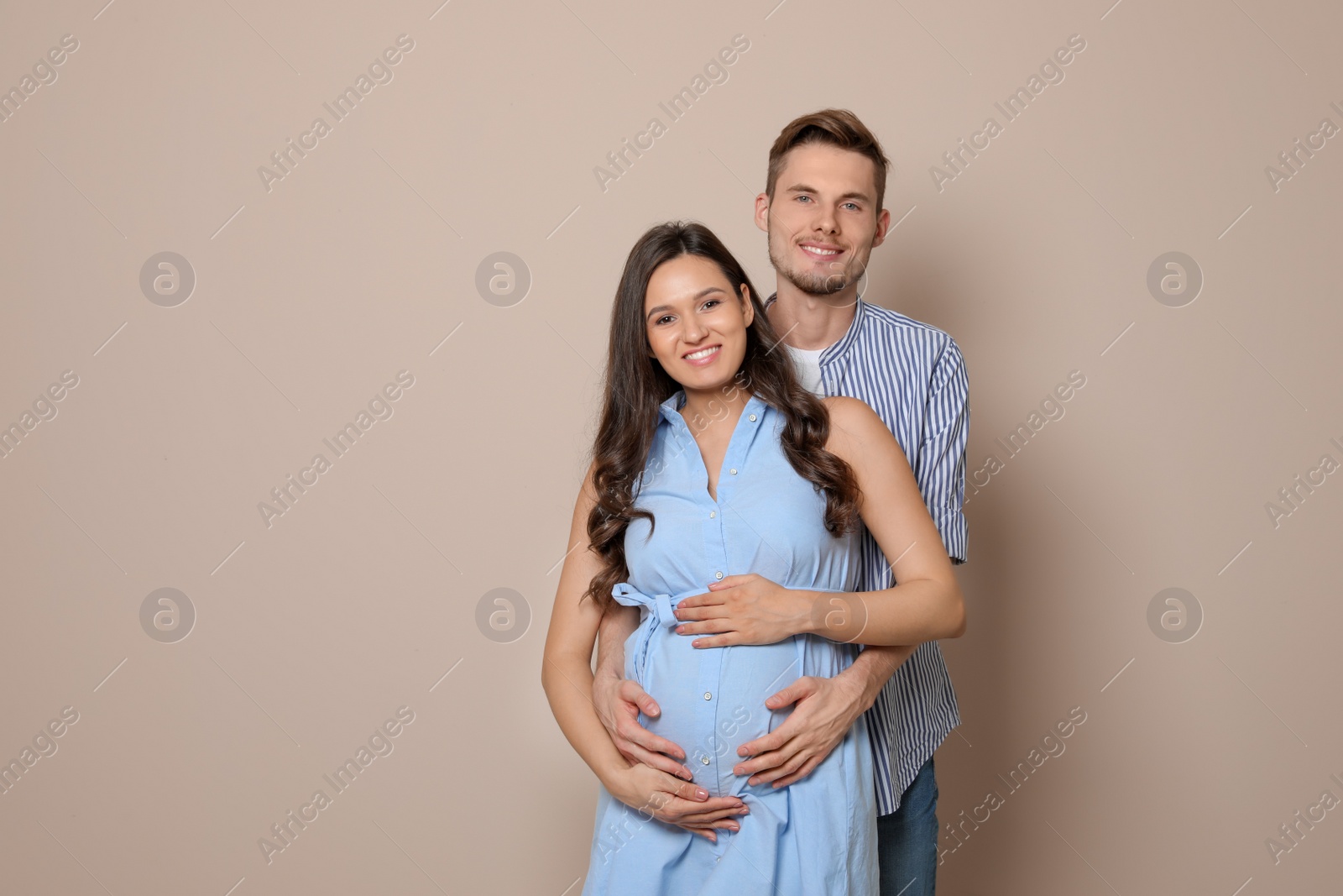 Photo of Pregnant woman and her husband on color background