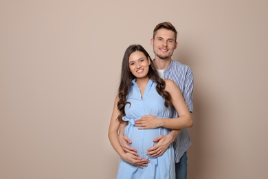 Pregnant woman and her husband on color background