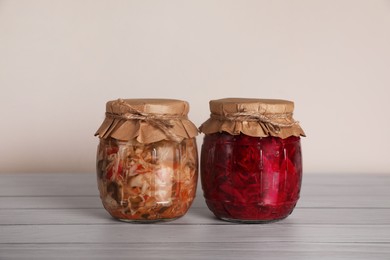 Photo of Jars with pickled vegetables on white wooden table
