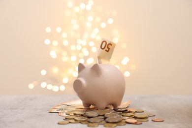 Piggy bank with euro banknote and coins on grey table against blurred lights