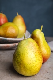 Photo of Ripe juicy pears on grey stone table against blue background