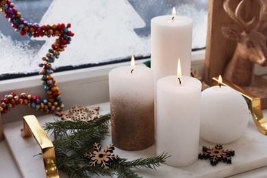 Photo of Beautiful burning candles with Christmas decor on windowsill indoors