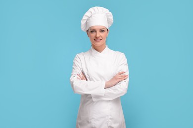 Photo of Happy chef in uniform on light blue background