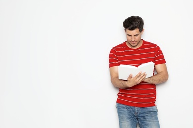 Photo of Handsome man reading book on white background, space for text