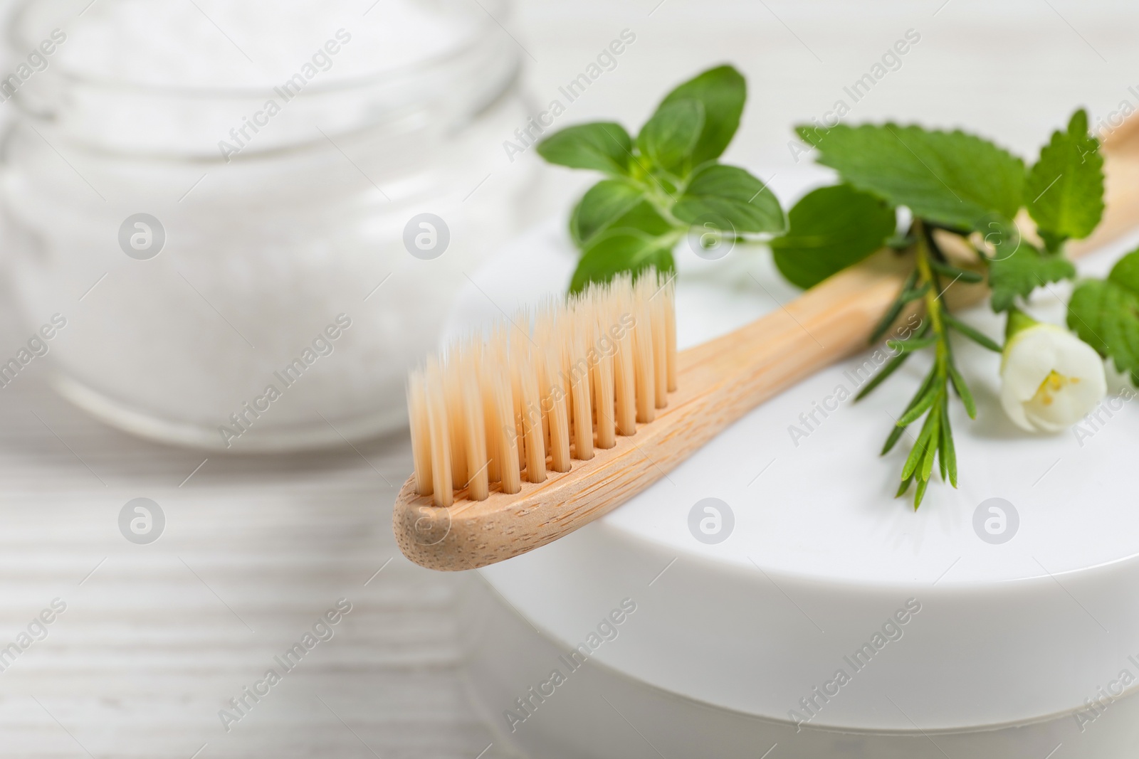 Photo of Toothbrush, dental products and herbs on white wooden table, closeup