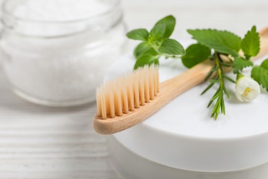 Toothbrush, dental products and herbs on white wooden table, closeup