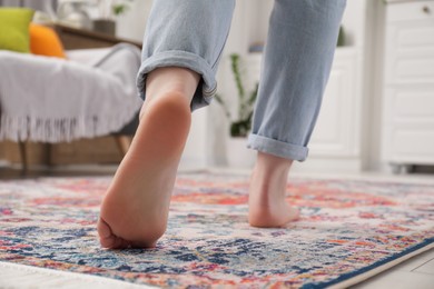 Photo of Woman standing on carpet with pattern in room, closeup