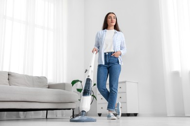 Photo of Woman cleaning floor with steam mop at home, low angle view