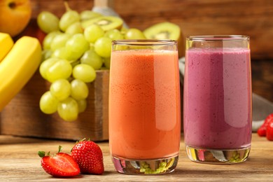 Photo of Glasses with different tasty smoothies and ingredients on wooden table