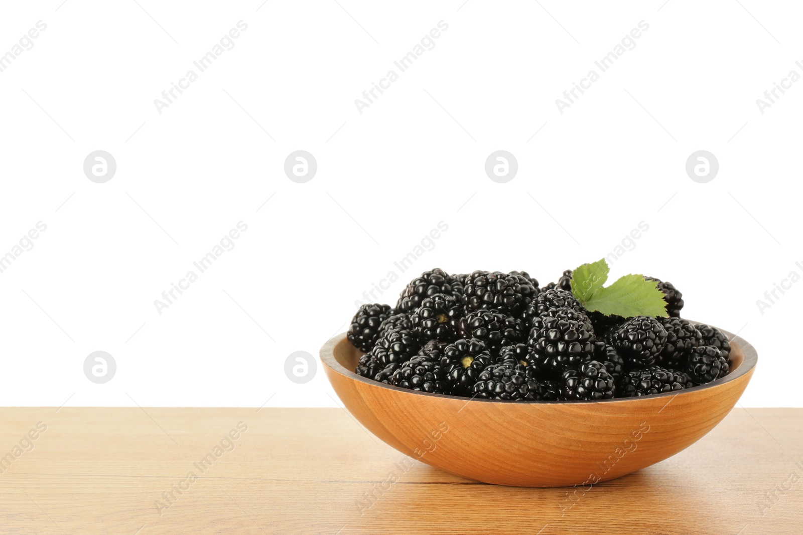 Photo of Bowl with fresh ripe blackberries on wooden table against white background, space for text