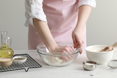 Woman kneading dough at white wooden table in kitchen, closeup. Cooking traditional grissini