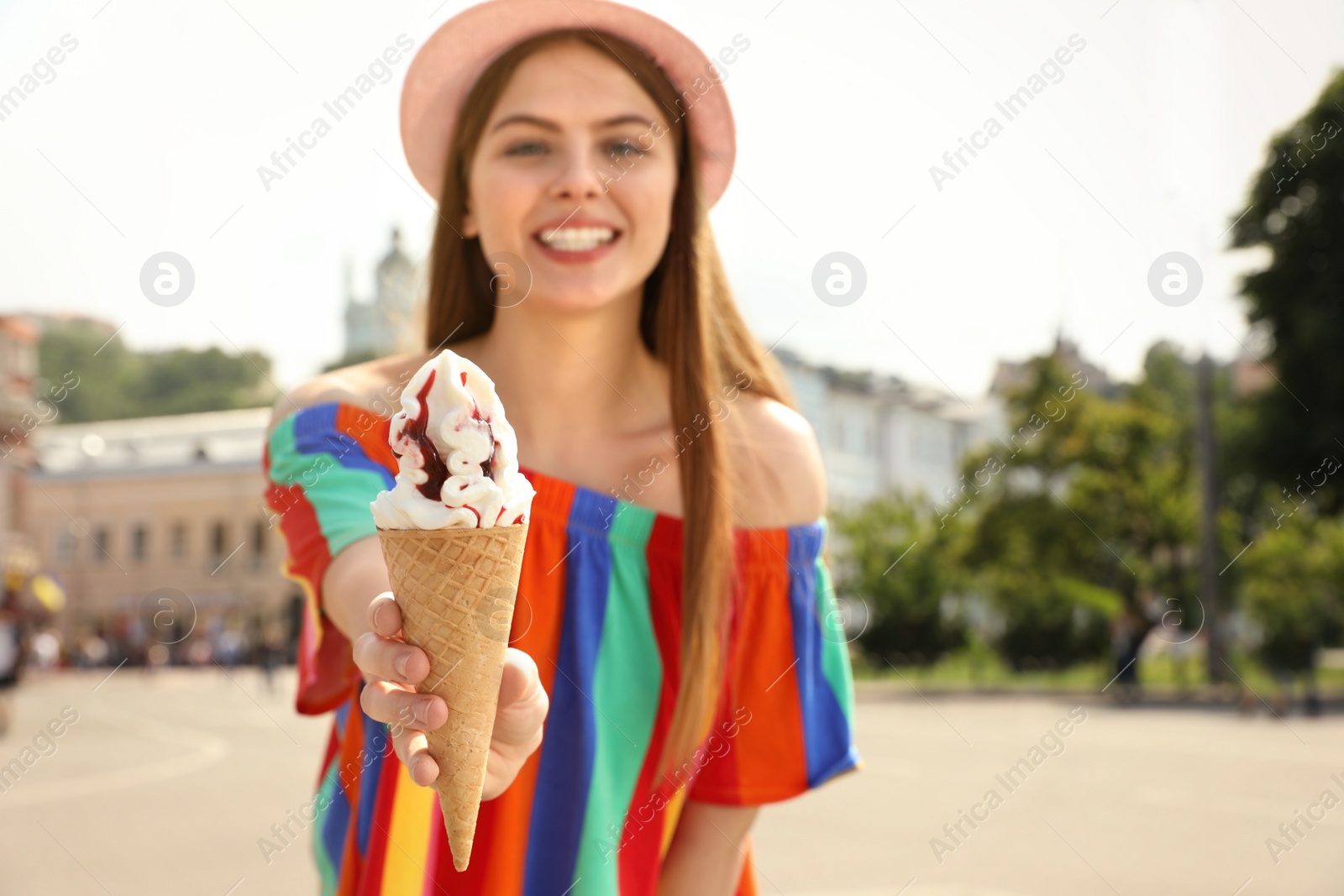 Photo of Young happy woman with ice cream cone on city street. Space for text