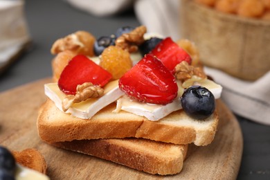 Photo of Tasty sandwich with brie cheese, fresh berries and walnuts on grey table, closeup