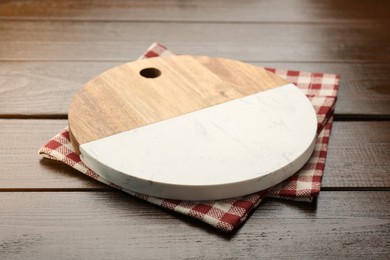 Photo of New cutting board and kitchen towel on wooden table